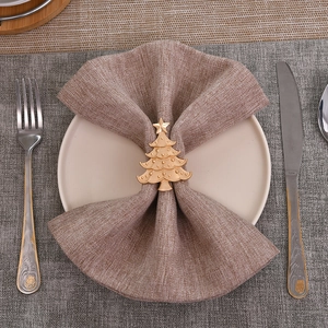 Golden Christmas tree metal napkin ring on white plate with silver cutlery set