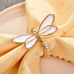 Golden dragonfly napkin ring with white enamel wings on a yellow table linen decor