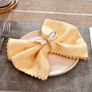Detailed close-up of a gold dragonfly napkin ring with white enamel wings and rhinestones