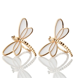 Detailed close-up of golden dragonfly napkin rings with white enamel wings and mirror reflection