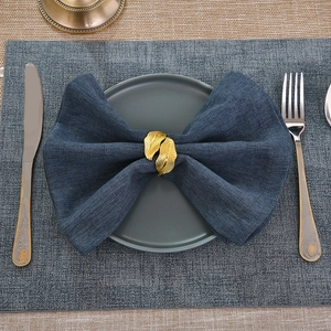 Golden leaf napkin ring on blue linen napkin set on a grey plate for table decor