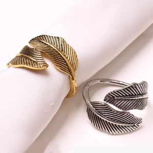 Macro detail of feather-shaped napkin rings in vintage gold and antique silver metal