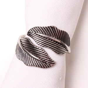 Close-up of silver vintage leaf napkin ring with detailed texture on a white cloth