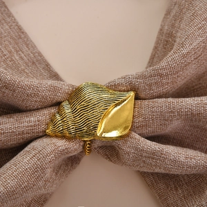 Gros plan sur un rond de serviette coquillage doré avec texture en spirale sur lin