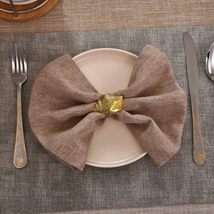 Rond de serviette doré en forme de conque sur serviette en lin et assiette blanche