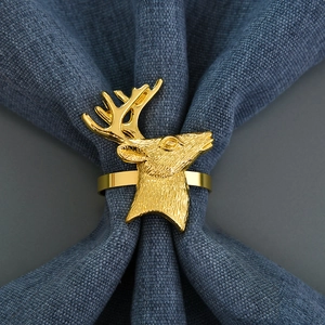 Close-up of golden reindeer head napkin ring with relief texture on a blue fabric napkin