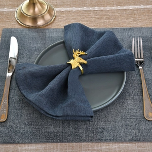 Detailed close-up of golden deer head napkin ring on a dark blue fabric napkin