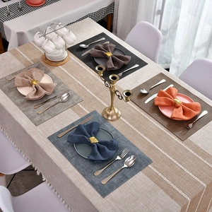 Ronds de serviette conque dorée sur nappe à rayures avec des glands et sets de table