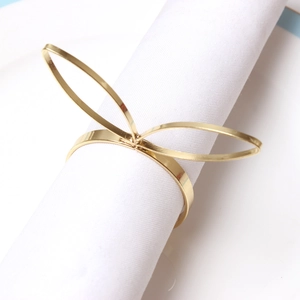 Polished gold rabbit ear metal napkin ring with bow shape on a white fabric napkin