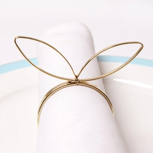 Golden bunny ear metal napkin rings on white fabric for elegant dining table decor