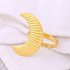 Elegant gold crescent moon napkin ring with ribbed metal texture on white linen