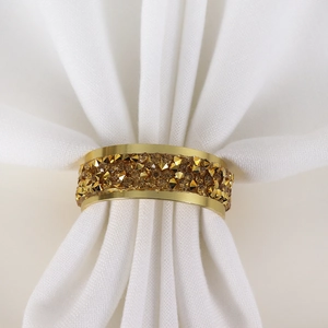 Elegant gold alloy napkin ring with amber crystals on a white fabric napkin decoration