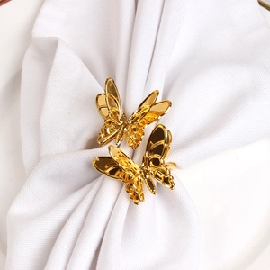 Elegant gold butterfly napkin ring set with hollow wings on white fabric for wedding decor