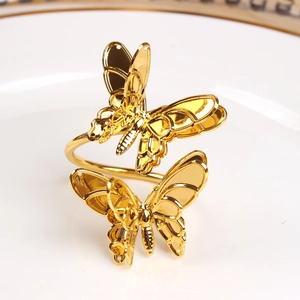 Elegant gold butterfly napkin ring set on a white ceramic tray for wedding table decor