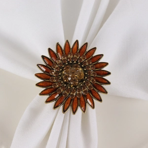 Vintage bronze sunflower napkin ring with amber rhinestones on a white linen cloth
