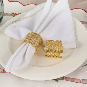 Modern hollow gold woven mesh napkin rings set of two displayed on a white plate