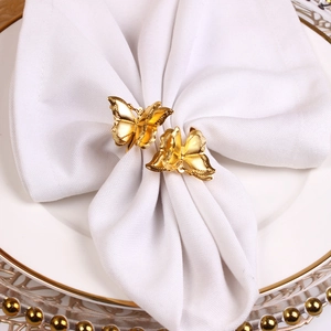 Elegante goldene Doppelschicht-Schmetterlings-Serviettenringe auf weißem Tischgedeck