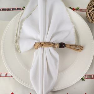 Handcrafted woven napkin ring with natural wooden bead on white fabric napkin
