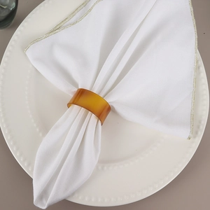 Rond de serviette minimaliste en résine ambrée sur serviette blanche et assiette