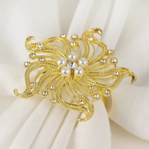 Dettaglio di un portatovagliolo a fiore dorato con eleganti perle e strass luccicanti