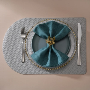 Detailed top view of golden coral napkin ring on dark green cloth and woven placemat