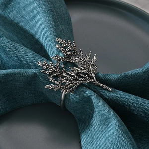 Retro coral branch alloy napkin ring with antique silver finish on a blue textured cloth