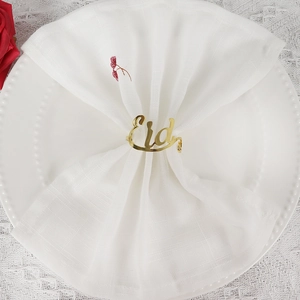 Elegant gold metal Eid Mubarak napkin ring with script lettering on a white plate
