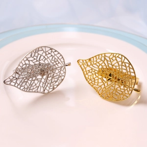 Elegantes servilleteros de hoja hueca en oro y plata sobre un plato de cerámica blanca
