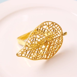 Elegante servilletero dorado con forma de hoja calada sobre un plato blanco de lujo