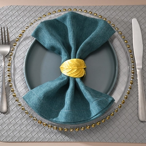 Golden leaf napkin ring detail with natural veins and elegant metal finish on a navy napkin
