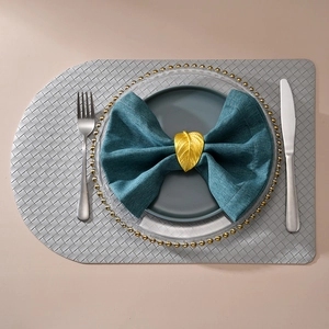 Golden leaf napkin ring with detailed vein texture on blue napkin with elegant plating