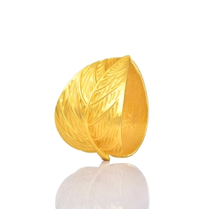 Polished gold leaf napkin ring with detailed vein patterns on a reflective white surface