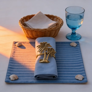 Golden palm tree napkin ring on blue linen napkin with tropical beach table setting