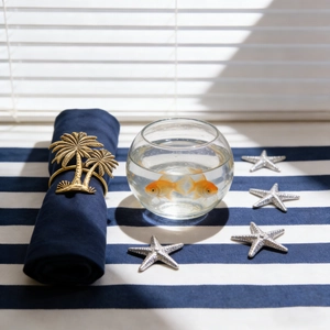 Detailed close-up of a gold coconut tree metal napkin ring on a blue fabric napkin