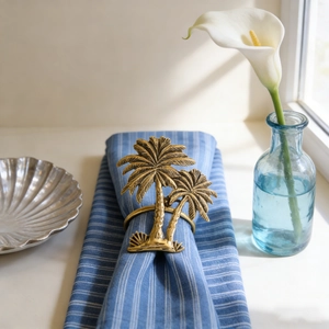 Retro golden coconut tree napkin ring with blue striped cloth on an elegant table