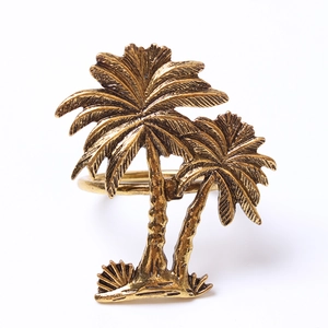 Close-up of vintage gold coconut tree napkin ring with intricate leaf details and metal texture