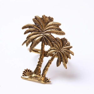 Detailed view of vintage gold metal napkin ring featuring tropical palm tree design