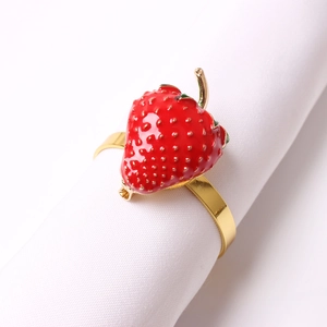 Dettaglio del portatovagliolo a forma di fragola smaltata rossa su tovagliolo bianco