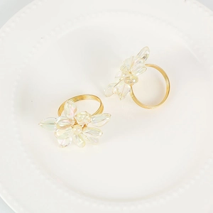 Elegante portatovagliolo in metallo dorato con petali di cristallo su piatto bianco