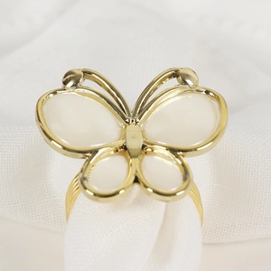 Elegant gold butterfly napkin ring with white faux shell inlay on white cloth
