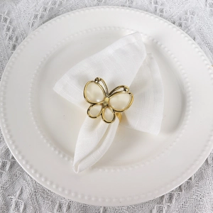 Golden butterfly napkin ring with white acrylic shell wings on a formal dining plate