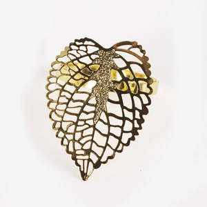 Golden hollowed-out leaf napkin ring with intricate vein pattern on a white backdrop