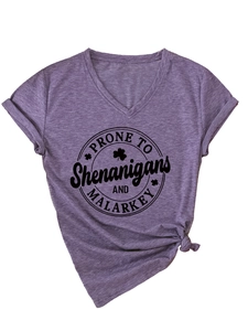 Détail d'un t-shirt violet à col en V avec impression festive et motif de trèfles