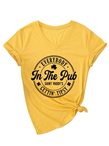 Detail eines gelben V-Ausschnitt T-Shirts mit festlichem Aufdruck und modischem Knotendesign