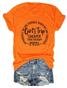 Flat lay of women's orange graphic t-shirt and light blue ripped denim shorts outfit