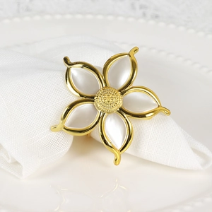 Portatovagliolo dorato a forma di fiore con petali bianco perla su tovagliolo bianco