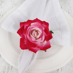 Top view of handmade pink gradient fabric rose napkin ring on a white plate with lace cloth