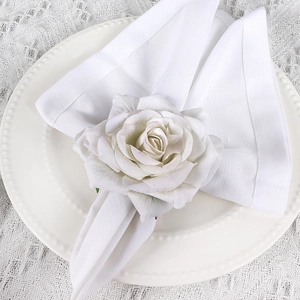 Detail of elegant white fabric rose napkin ring on a scalloped ceramic plate