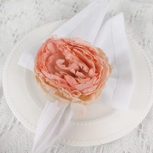 Detail shot of a peach-pink fabric rose napkin ring on a white plate with lace