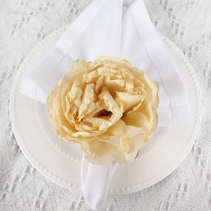 Elegant cream rose fabric napkin ring on a white decorative plate for wedding tables